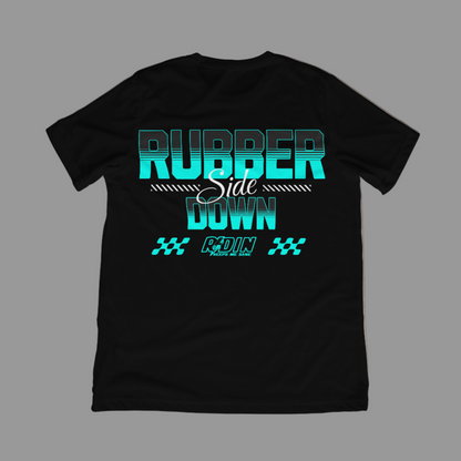 Black t-shirt with teal and white text on a concrete floor