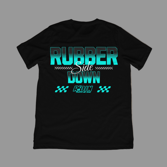 Black t-shirt with teal and white text on a concrete floor